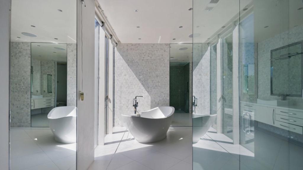 Modern bathroom with a freestanding tub, glass shower enclosure, large windows, and white tile, supporting a shower vs tub remodel guide for San Diego homes