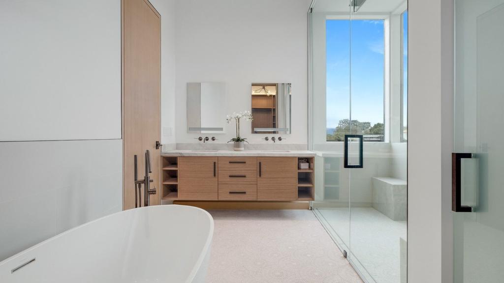 Bright modern bathroom with a freestanding tub, double vanity, glass shower enclosure, and large window for a San Diego bathroom remodel cost guide
