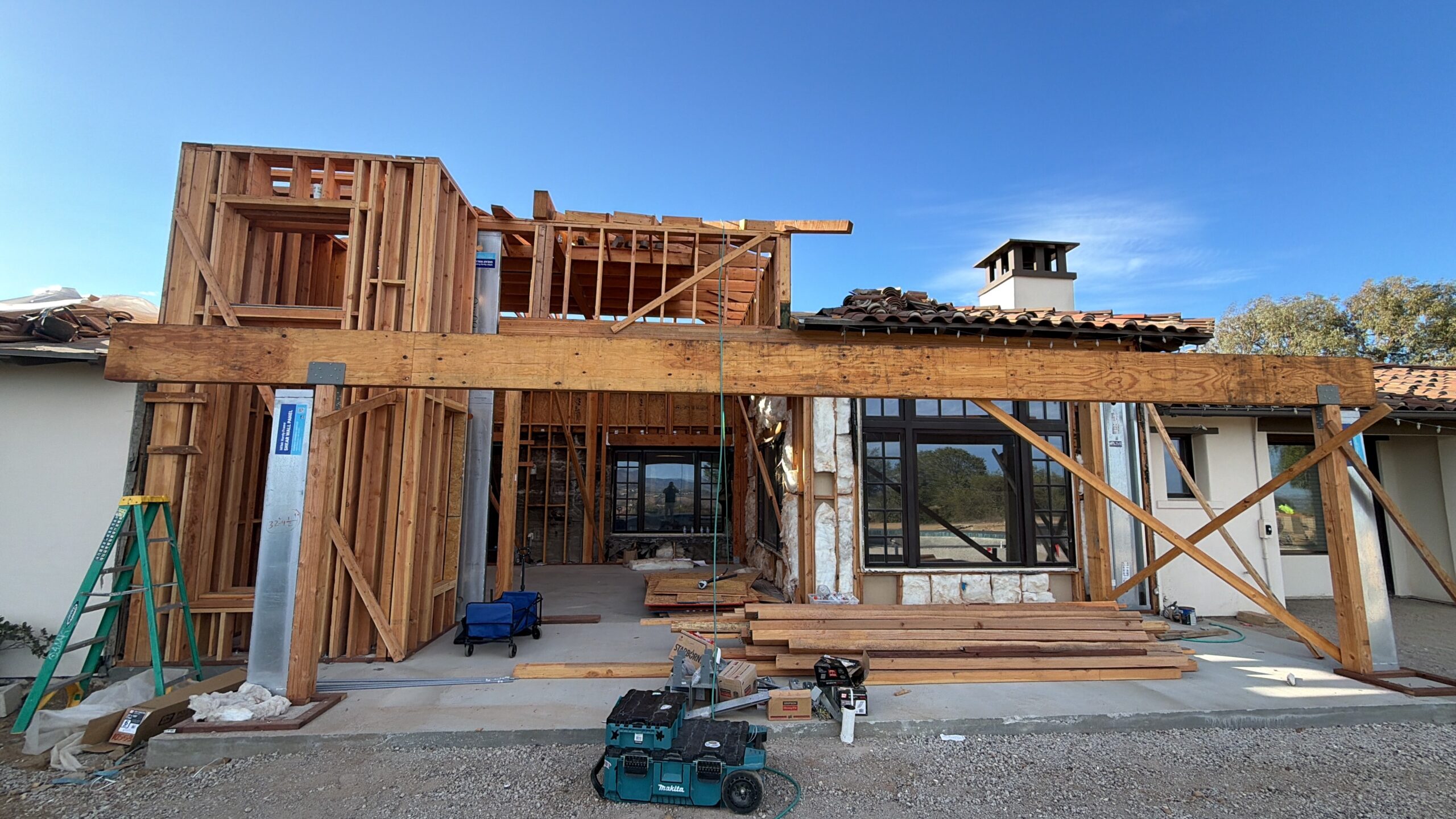 Home remodeling San Diego project showing a Mediterranean estate with new wood framing, structural beams, windows, and second-story construction.